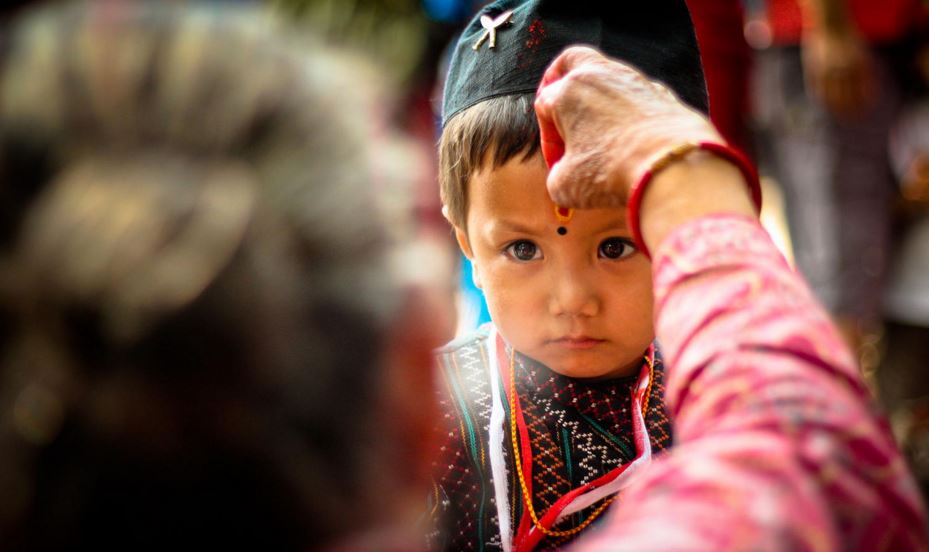 Little kids receives tika put on his forehead by an elderly woman in Suryabinayak, Bhaktapur.