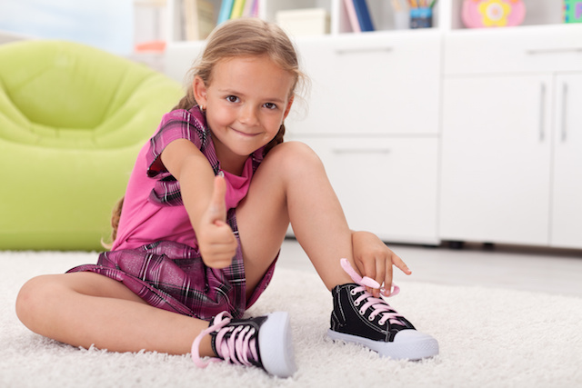 Little girl learning how to tie her shoes, being proud of herself