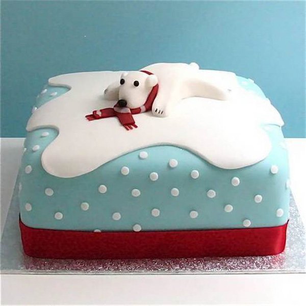 Polar bear inspired Christmas cake. The cake looks like the snowy terrains of the north pole as the polar bear is happily sliding around on the white cold snow.