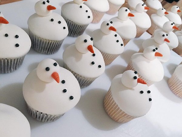 Snowman inspired Christmas cupcakes. The cupcakes are designed to resemble a snowman with buttons and a carrot nose. It looks yummy and at the same time adorable.