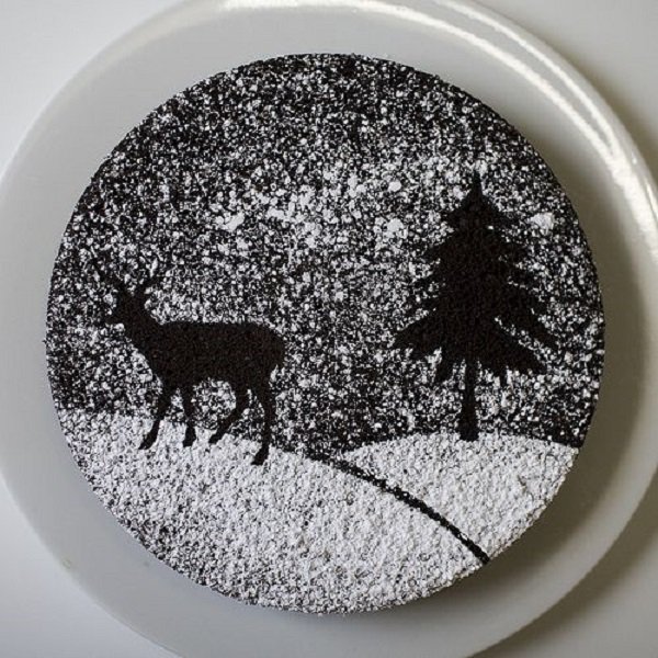 Beautiful looking Christmas cake with a silhouette design. The design on top has been made to look like a peaceful snowy Christmas evening in the woods with pine trees and a solitary deer roaming around.
