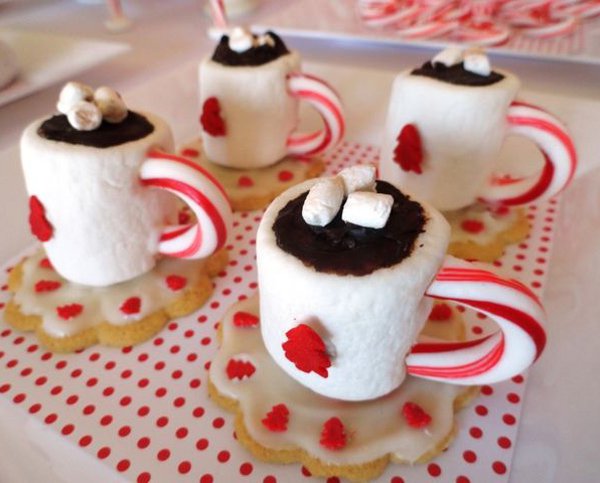 Pretty looking tea Christmas cupcakes. The mini cakes have been made to look like small mugs of hot choco with marshmallows on top and candy canes as the mug handle.