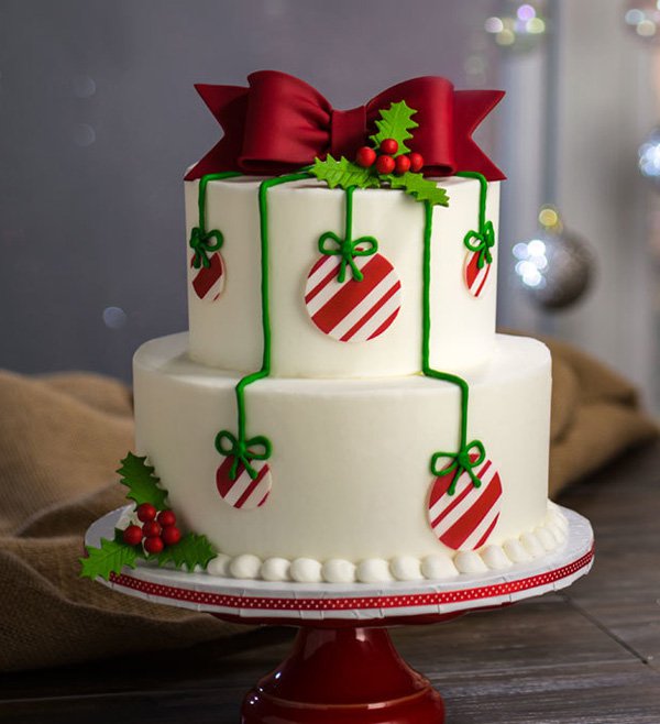 Christmas tree themed Christmas cake. The Christmas cake is designed to look like a Christmas tree complete with a mistletoe and Christmas balls hanging around the tree. On top the icing has been designed to look like a ribbon.