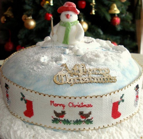 Beautiful looking Christmas cake. The Christmas cake is designed to look like a snow filled lawn with snow sprinkles surrounding a modest looking snowman with a hat and scarf.