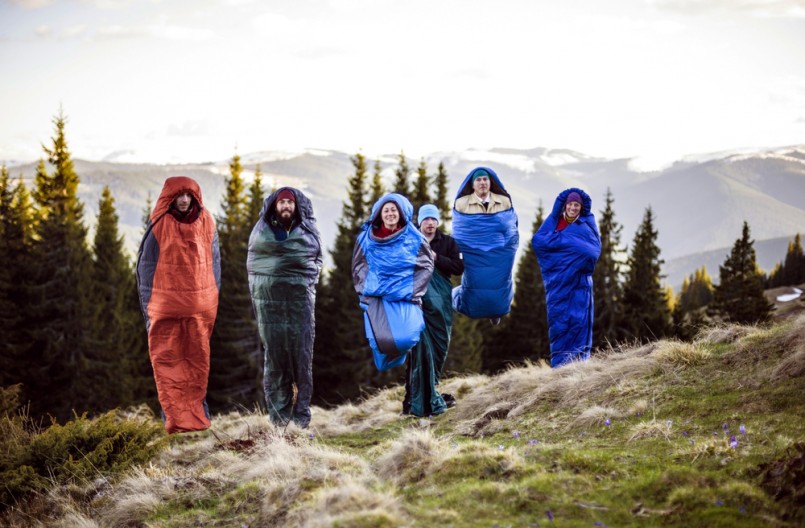 cheering-group-of-hikers-jumping-in-sleeping-bags-outdoors-in-mountains-during-the-sunset-805x528